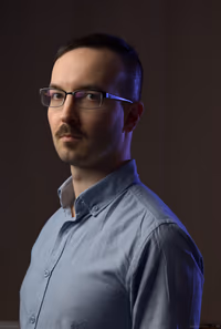 Studio self-portrait, softbox key and undiffused rim light; distant dark background for high contrast.